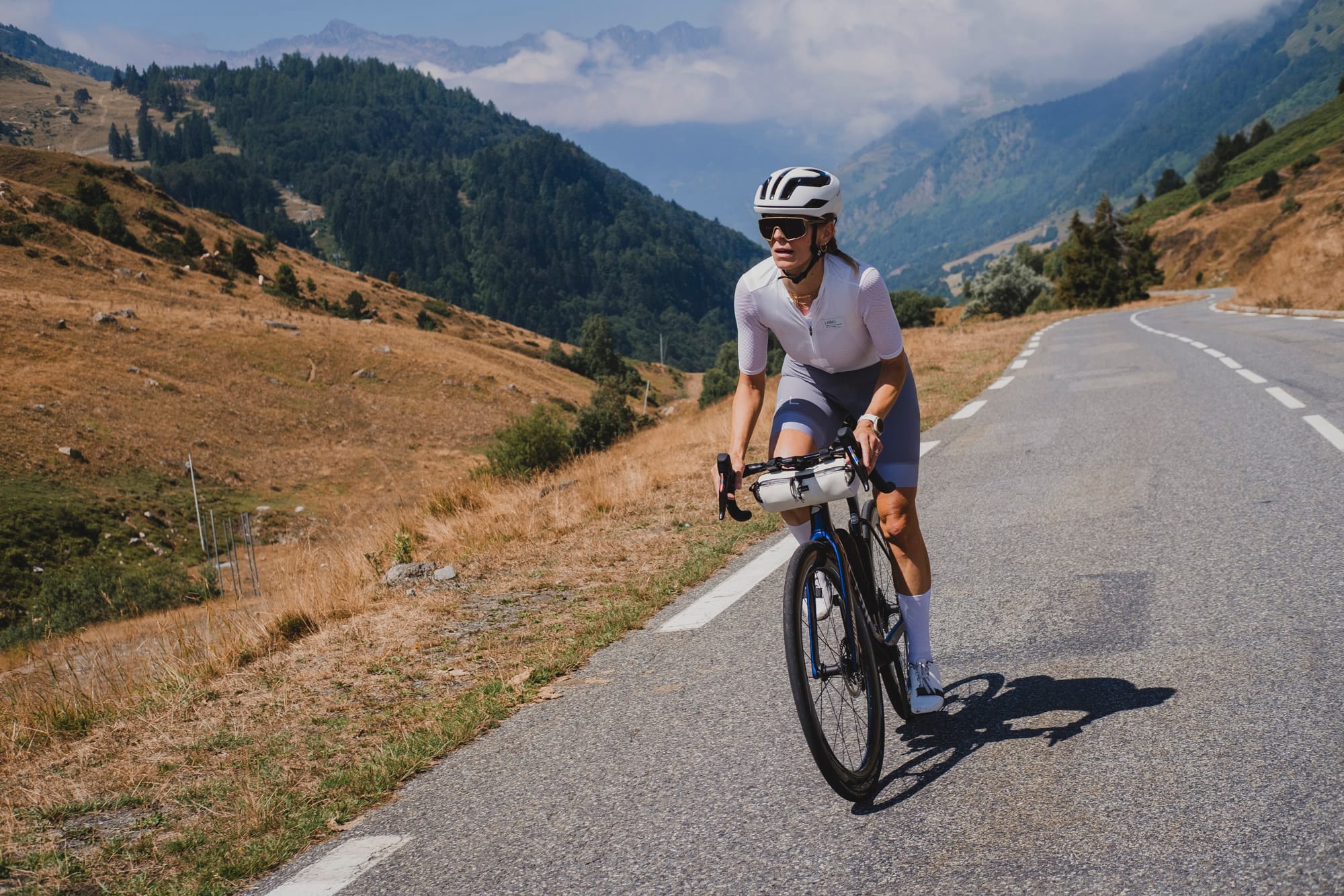 Eva cycling up the Col du Tourmalet, surrounded by high Pyrenean mountains and alpine scenery.